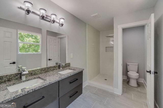 bathroom featuring vanity, toilet, and tiled shower