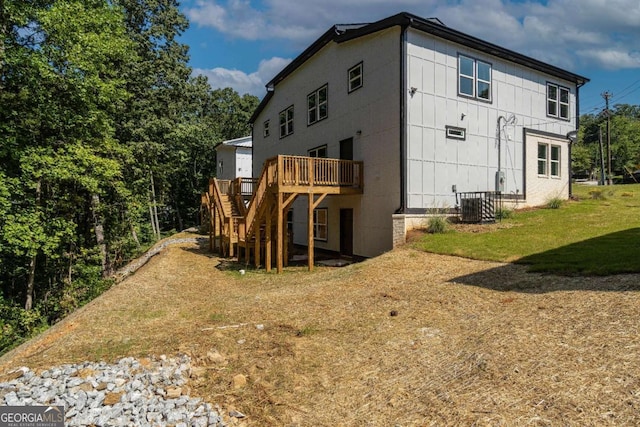 rear view of house featuring a wooden deck, a lawn, and central air condition unit