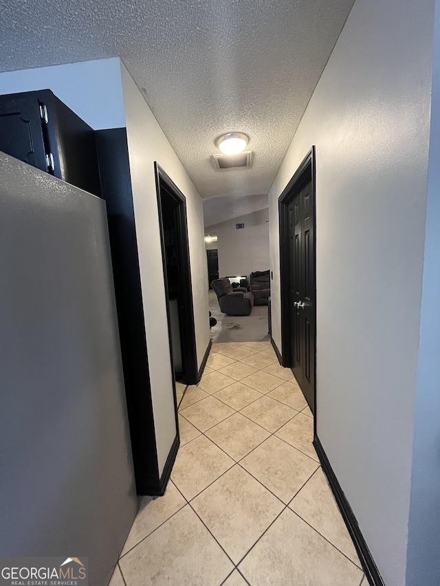 hall featuring light tile patterned floors and a textured ceiling