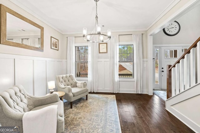 sitting room with dark wood-type flooring, ornamental molding, and a chandelier