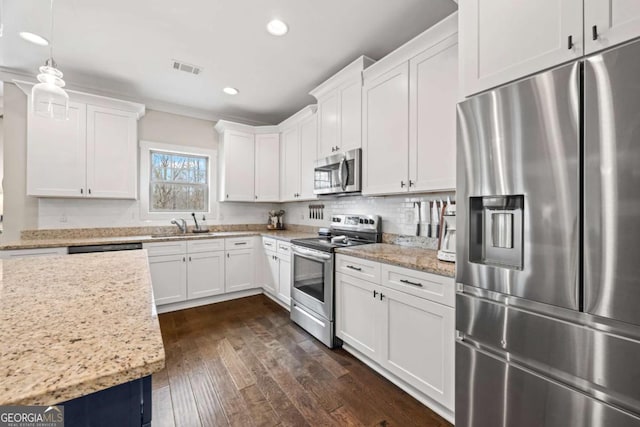 kitchen featuring white cabinetry, appliances with stainless steel finishes, light stone countertops, and hanging light fixtures