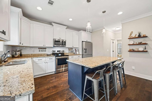 kitchen featuring white cabinetry, stainless steel appliances, decorative light fixtures, and a center island