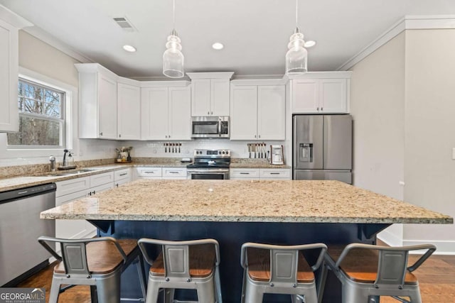 kitchen with pendant lighting, stainless steel appliances, and white cabinets