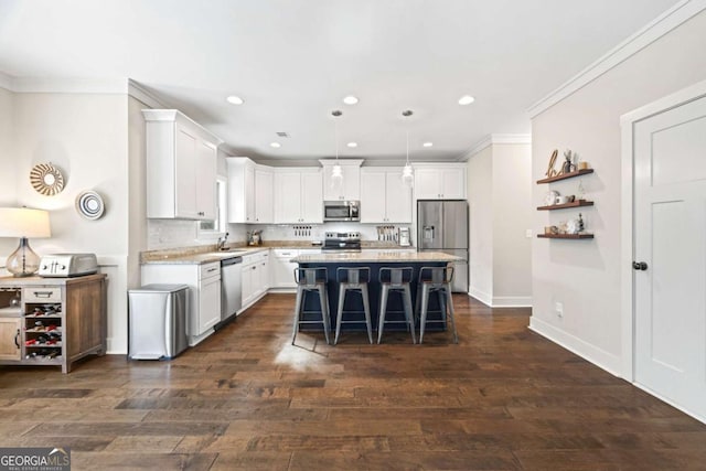 kitchen featuring sink, appliances with stainless steel finishes, hanging light fixtures, a center island, and a kitchen bar