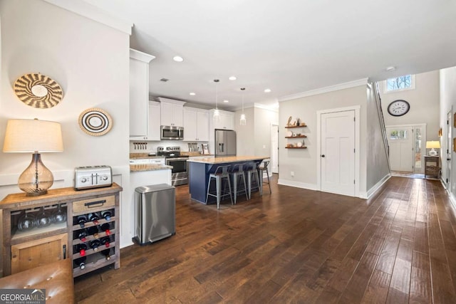 kitchen with a kitchen bar, dark hardwood / wood-style flooring, a kitchen island, stainless steel appliances, and white cabinets