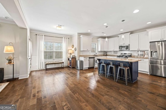 kitchen with a kitchen island, a breakfast bar, decorative light fixtures, white cabinetry, and stainless steel appliances