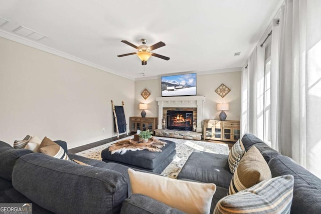 living room with a fireplace, ornamental molding, and ceiling fan