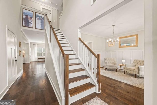 staircase with crown molding, hardwood / wood-style floors, a high ceiling, and a notable chandelier