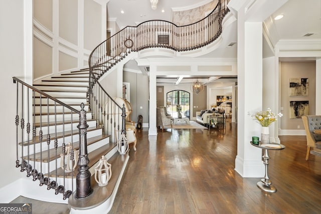 entryway with a towering ceiling, crown molding, baseboards, and dark wood-style flooring