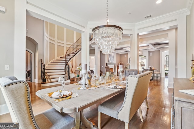 dining space featuring arched walkways, an inviting chandelier, wood finished floors, coffered ceiling, and stairs