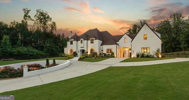 french country style house featuring driveway, a front lawn, and fence