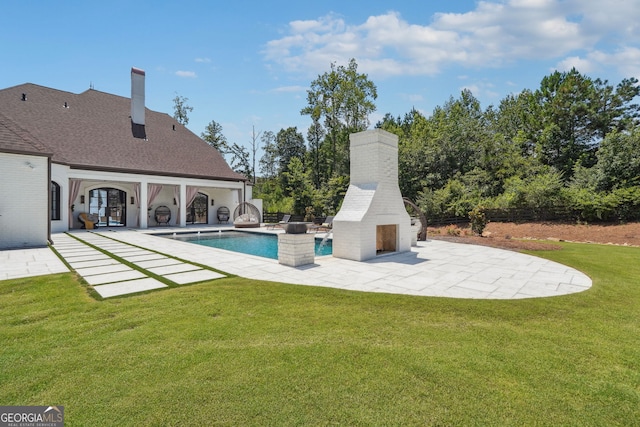 outdoor pool featuring a patio area, an outdoor brick fireplace, and a yard