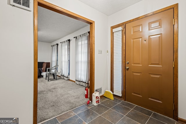 carpeted entryway with a textured ceiling