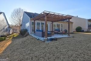 rear view of house featuring a pergola and a lawn