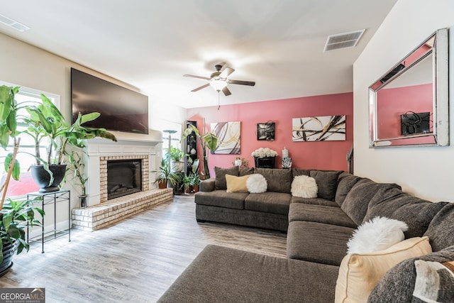 living room with ceiling fan, plenty of natural light, a fireplace, and light hardwood / wood-style floors