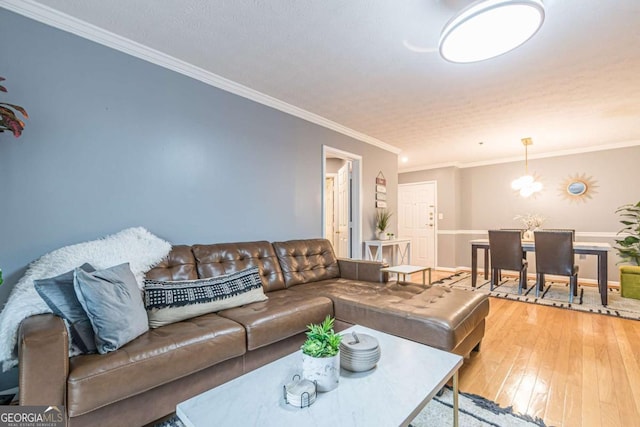 living room featuring a notable chandelier, ornamental molding, and light hardwood / wood-style floors