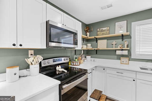 kitchen featuring appliances with stainless steel finishes, sink, hardwood / wood-style floors, and white cabinets