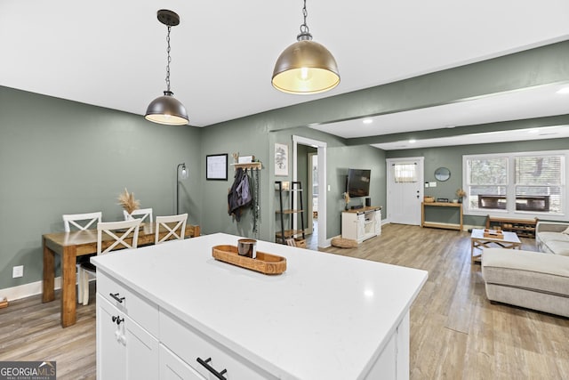 kitchen with pendant lighting, white cabinetry, a center island, and light hardwood / wood-style flooring