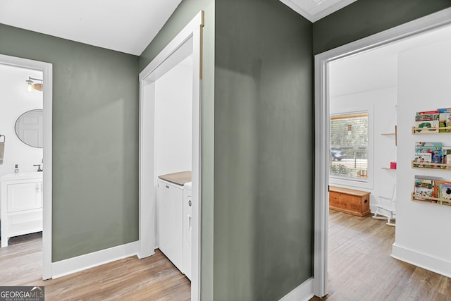 hallway with washer and clothes dryer and light hardwood / wood-style floors