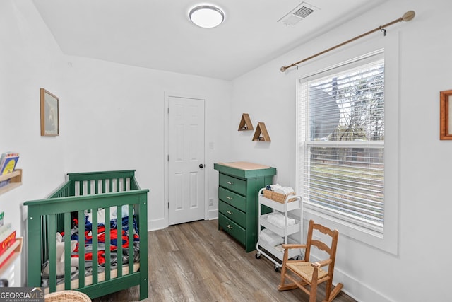 bedroom with a crib and light hardwood / wood-style flooring