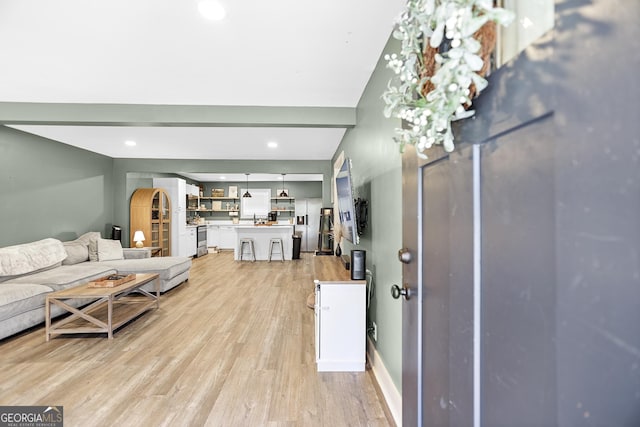 living room with beamed ceiling and light hardwood / wood-style floors