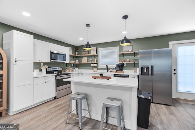 kitchen with sink, white cabinetry, a center island, stainless steel appliances, and light hardwood / wood-style floors