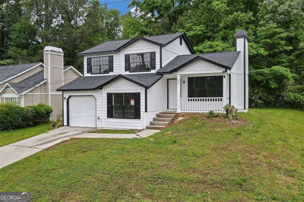 view of front of home featuring a porch, a garage, and a front lawn