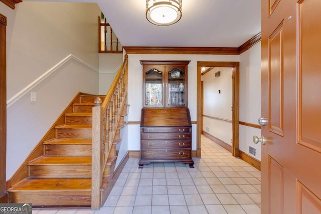 stairs with ornamental molding, visible vents, baseboards, and tile patterned floors