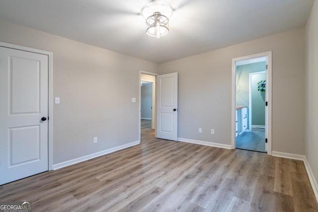 unfurnished bedroom with connected bathroom and light wood-type flooring