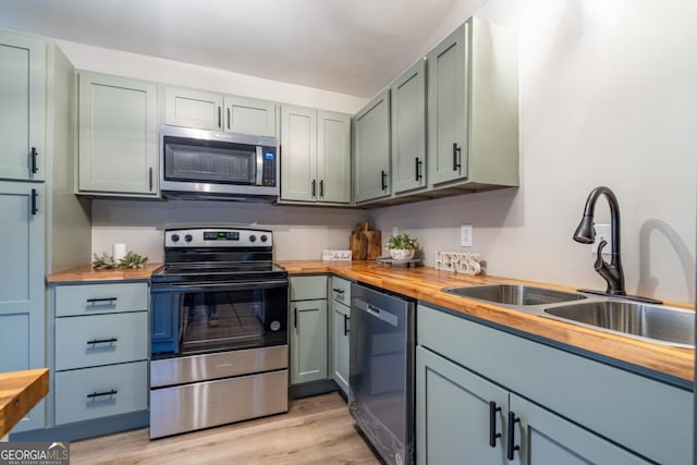 kitchen featuring appliances with stainless steel finishes, sink, wood counters, and light hardwood / wood-style flooring