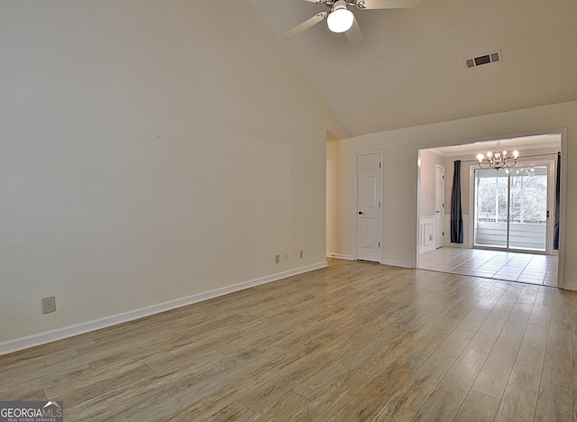 empty room with ceiling fan with notable chandelier, high vaulted ceiling, and light wood-type flooring