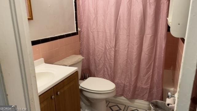 bathroom with vanity, toilet, and tile walls