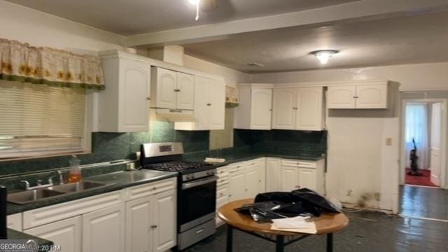 kitchen featuring white cabinetry, stainless steel gas range oven, sink, and decorative backsplash