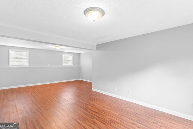 basement featuring hardwood / wood-style flooring and a textured ceiling