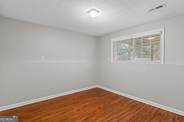 empty room with wood-type flooring and a textured ceiling