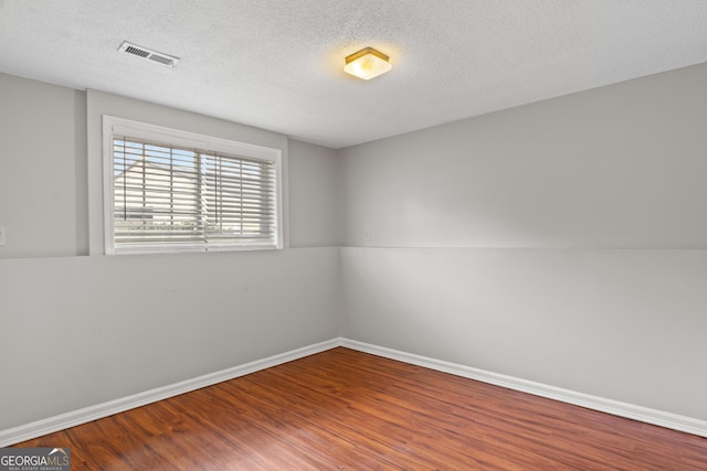 spare room with hardwood / wood-style floors and a textured ceiling