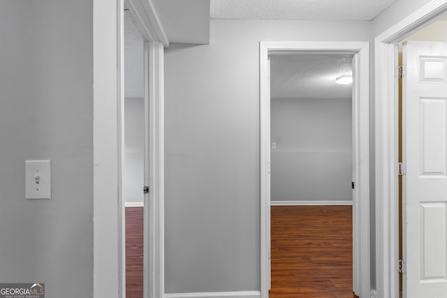 corridor featuring dark wood-type flooring and a textured ceiling