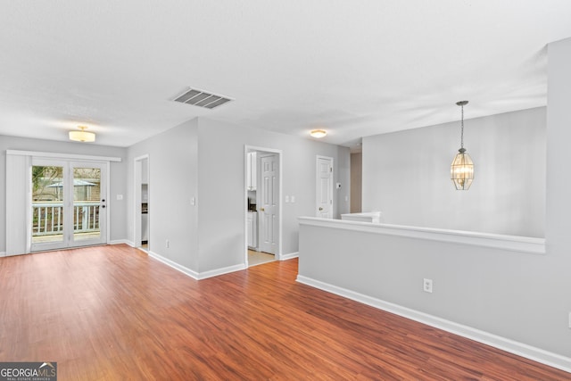 unfurnished room with a notable chandelier and light hardwood / wood-style floors