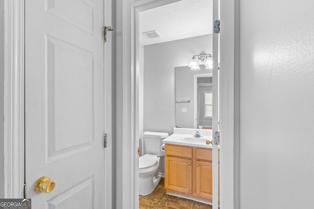 bathroom featuring vanity, a textured ceiling, and toilet