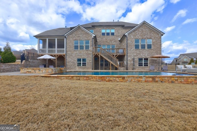 rear view of property featuring a sunroom, a yard, a deck, and a patio area