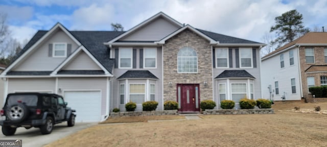 view of front facade featuring driveway, stone siding, and an attached garage