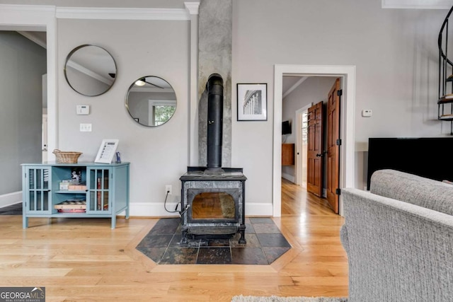 living room with ornamental molding, wood-type flooring, and a wood stove