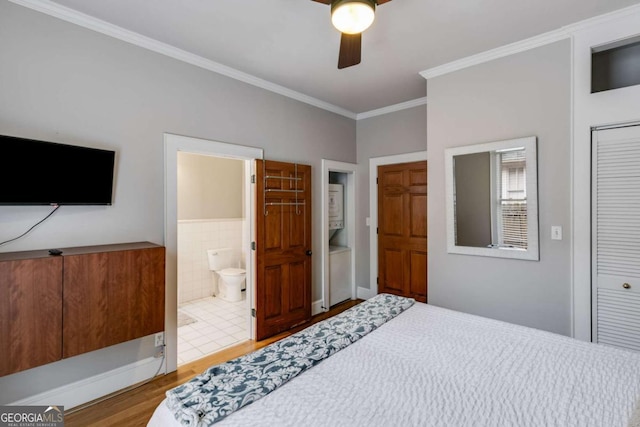 bedroom featuring hardwood / wood-style flooring, ceiling fan, tile walls, ornamental molding, and a closet