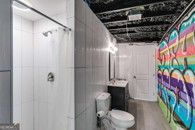 bathroom with vanity, tiled shower, tile walls, and toilet