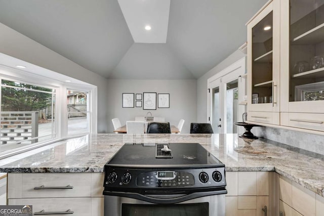 kitchen with lofted ceiling, light stone countertops, stainless steel range with electric cooktop, and light brown cabinets