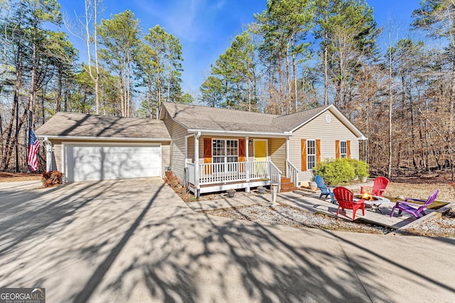 ranch-style home featuring a fire pit, a garage, and a porch