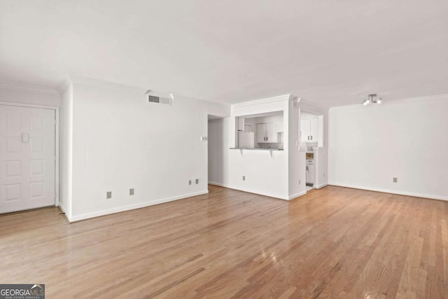 unfurnished living room featuring ornamental molding and light hardwood / wood-style floors