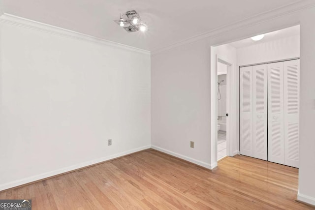 unfurnished bedroom featuring crown molding, a closet, and light wood-type flooring