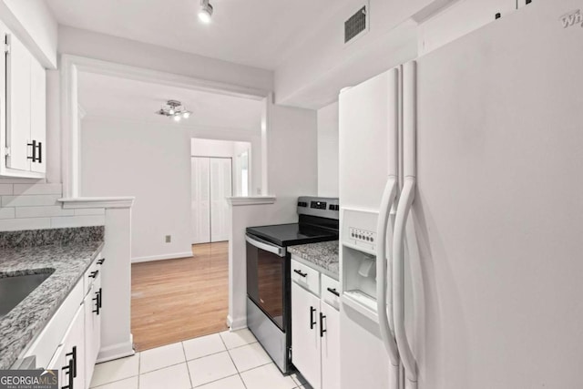 kitchen with white cabinetry, light stone counters, white refrigerator with ice dispenser, decorative backsplash, and stainless steel range with electric cooktop