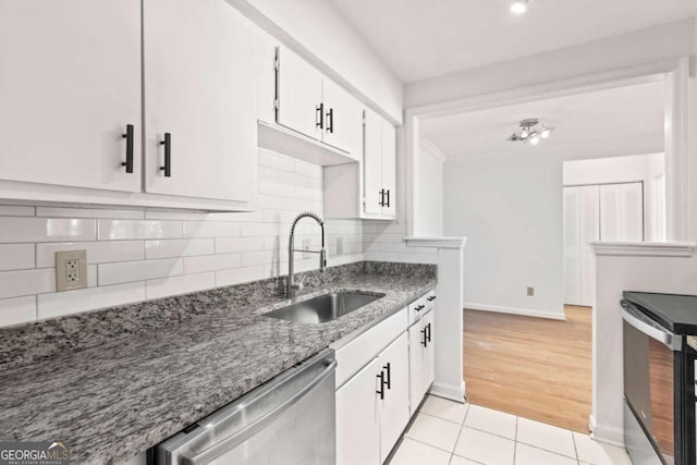 kitchen with light tile patterned flooring, sink, tasteful backsplash, stainless steel appliances, and white cabinets